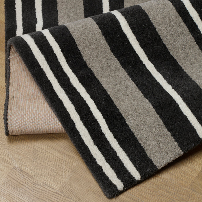 Modern rug with bold black, grey, and white stripes, offering a stylish and contemporary touch to any room.